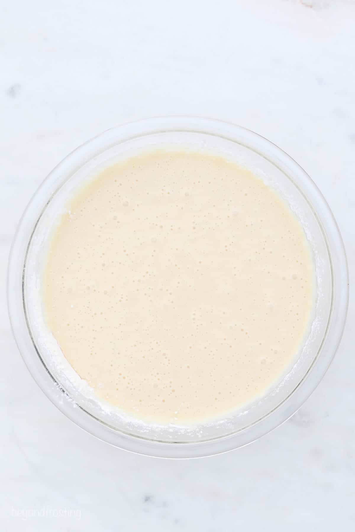 a glass mixing bowl with vanilla cupcake batter