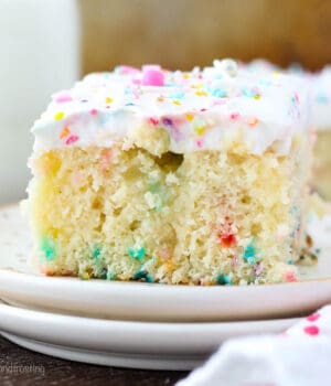A closeup of a sliced of Vanilla Funfetti Poke Cake with sprinkles
