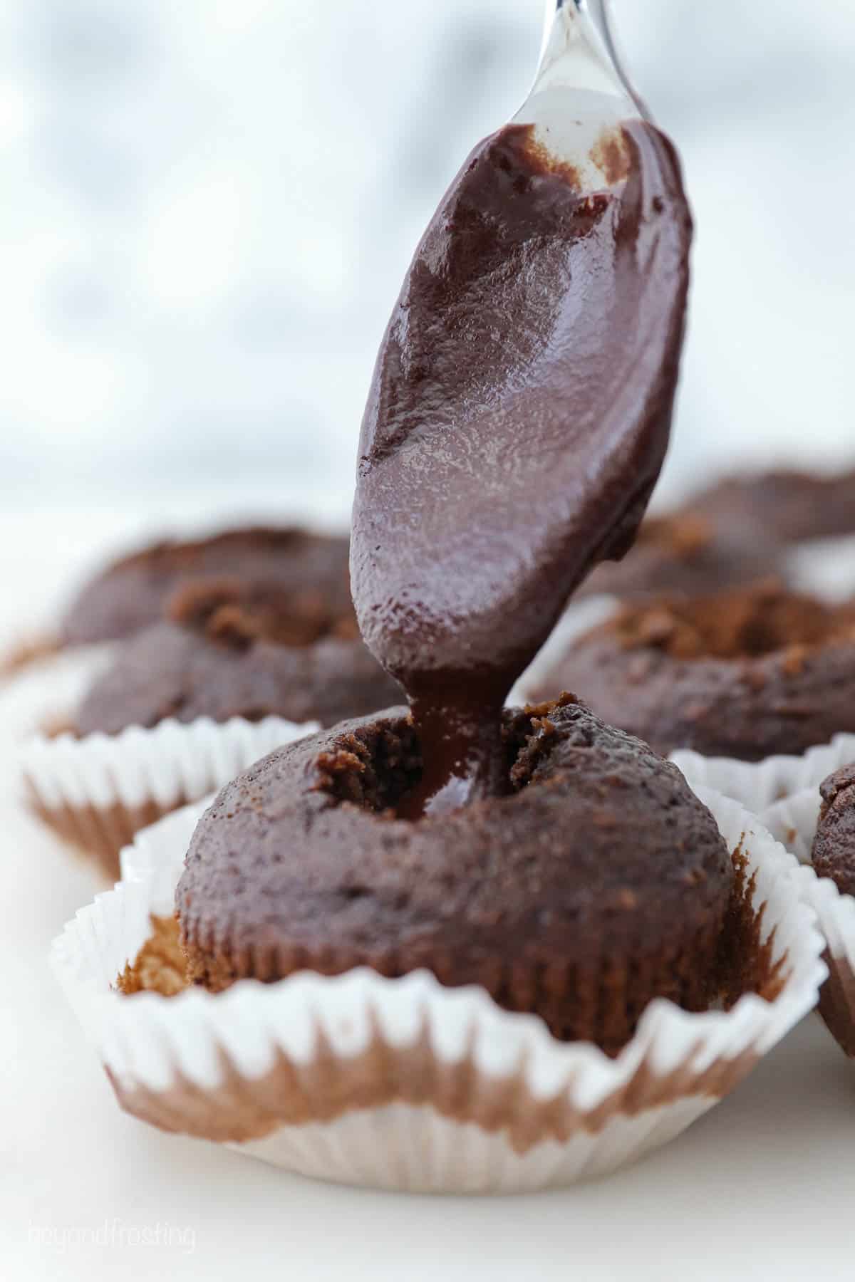 gluten-free chocolate cupcake being filled with chocolate ganache