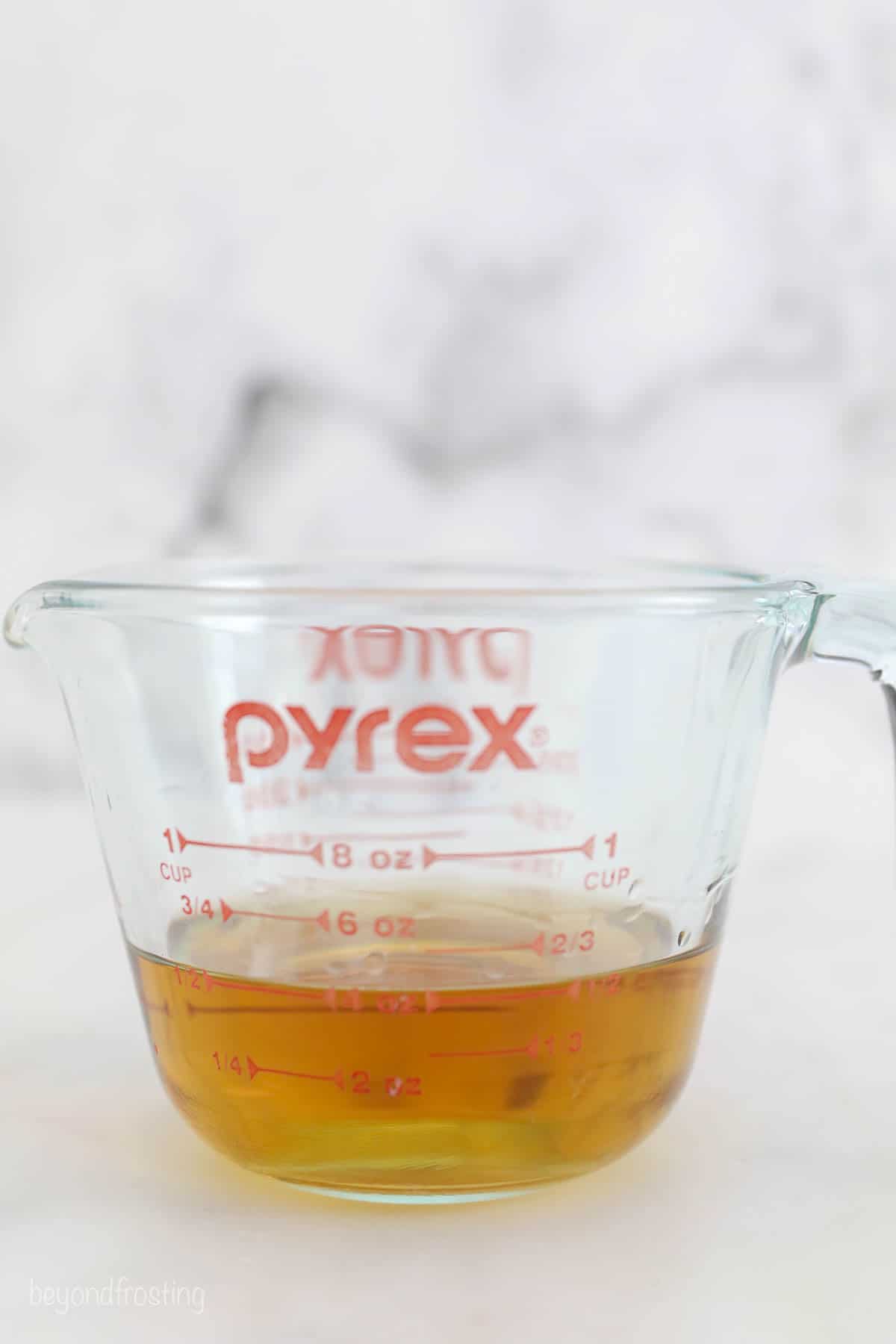 Half a cup of rum inside of a glass Pyrex measuring cup