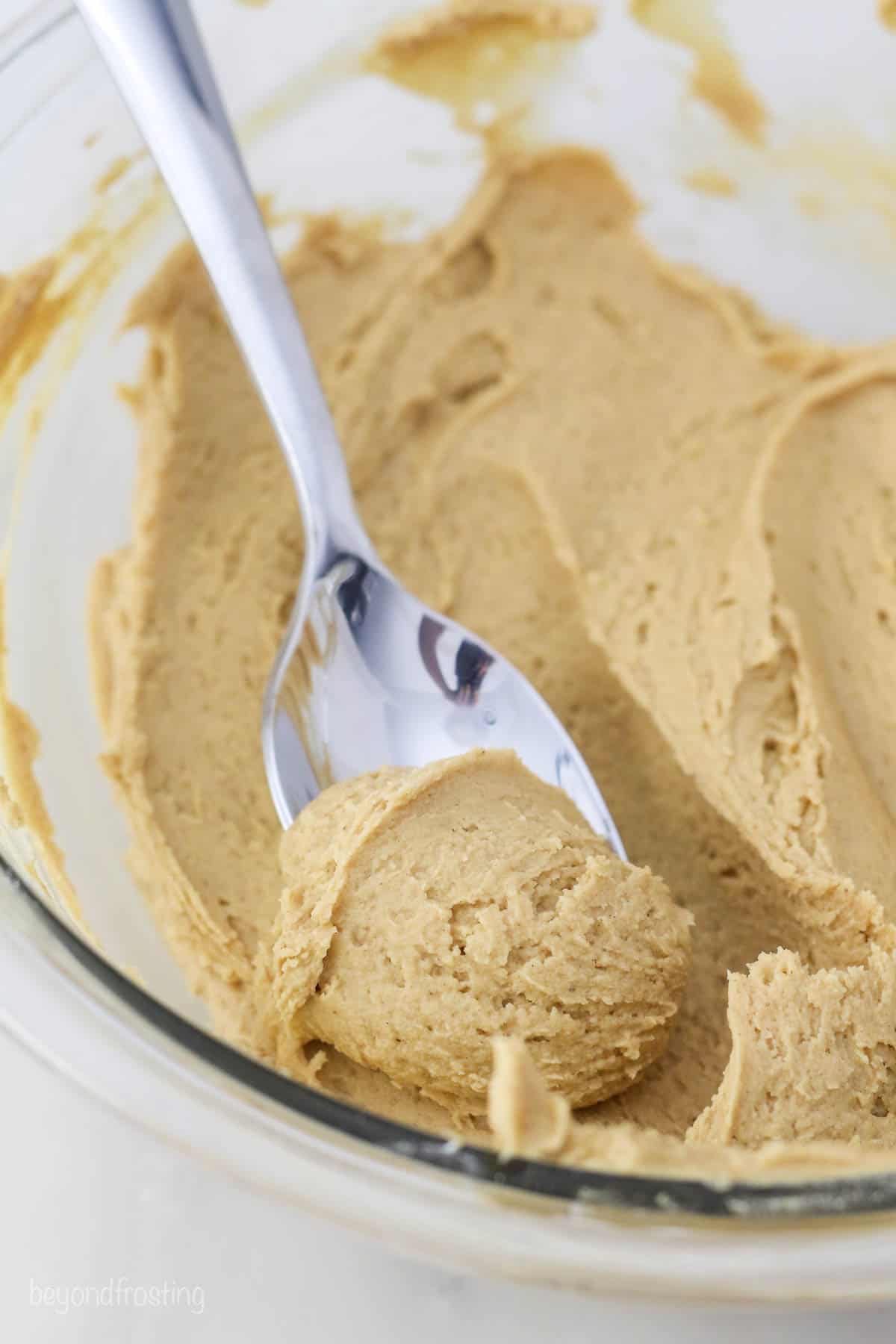 A silver spoon dipping into a bowl of peanut butter filler