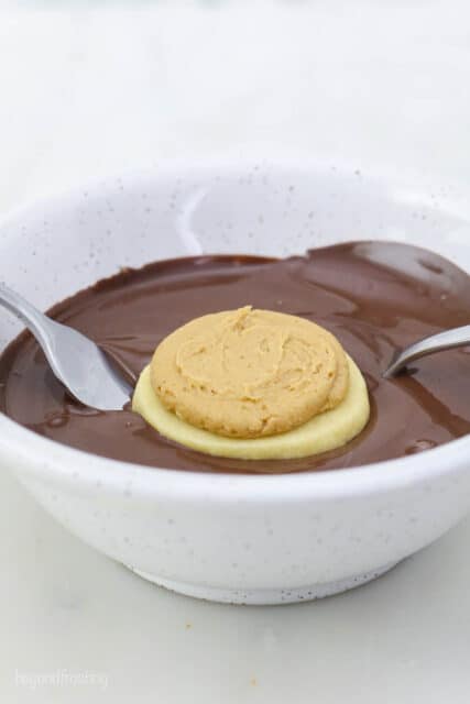 A fork dipping a cookie into a bowl of melted chocolate