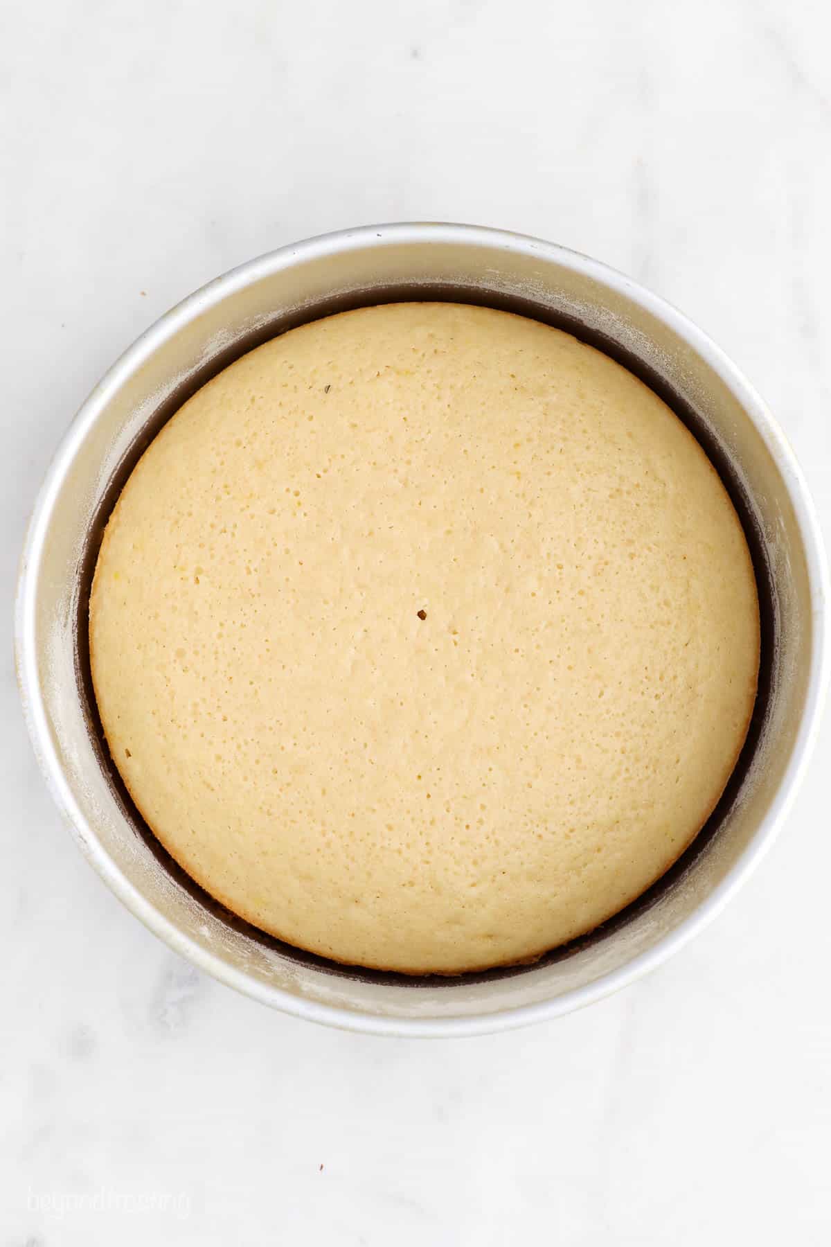 Birds eye view of a vanilla cake layer in a round pan