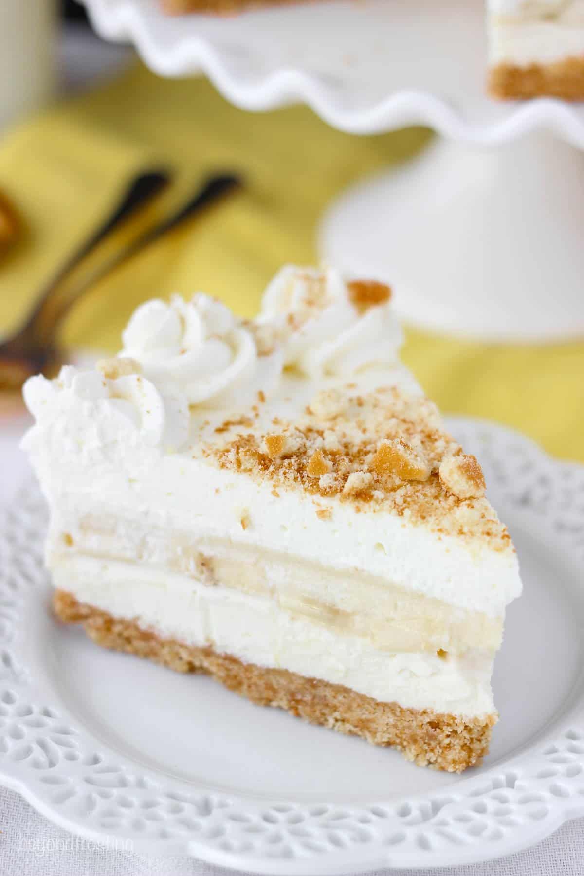 A slice of no-bake banana pudding cheesecake topped with Nilla wafer crumbs on a dessert plate
