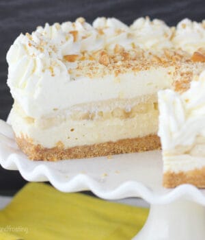 A close-up shot of a banana pudding cheesecake on a large platter with two slices missing