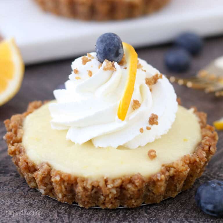 Close up of a lemon pudding tart topped with a swirl of whipped cream.