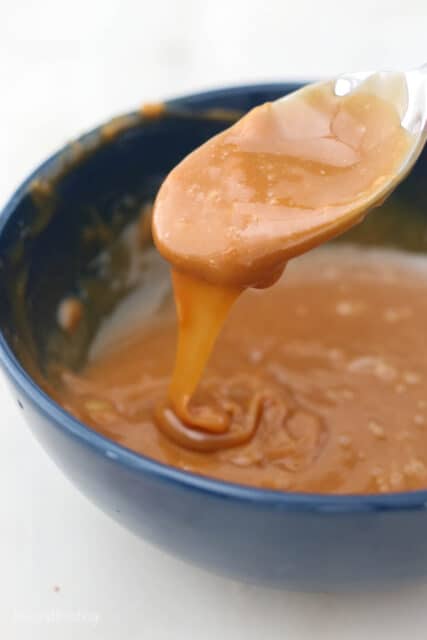 a spoonful of caramel being scooped out of a bowl