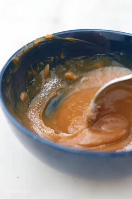 side view of a bowl of salted caramel with a spoon