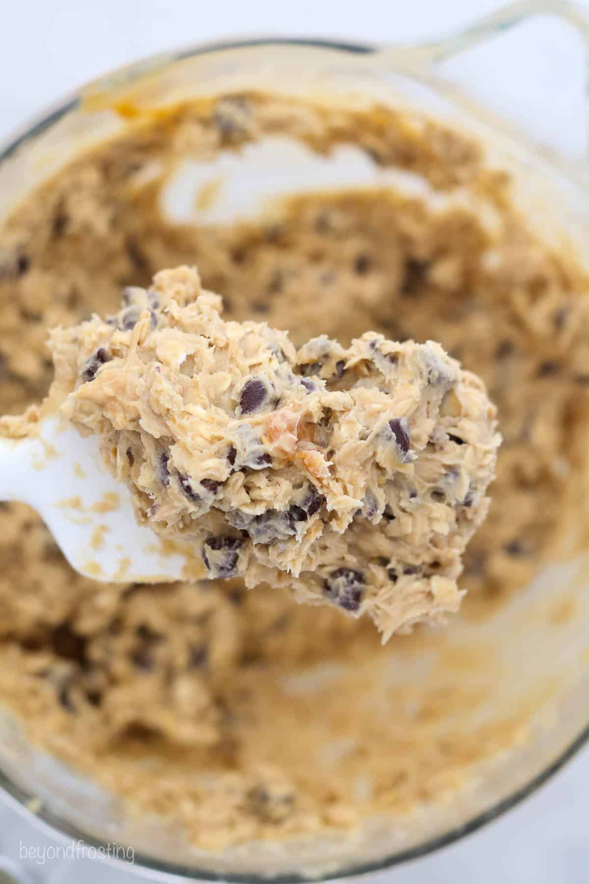 a spatula full of oatmeal cookie dough over a bowl of dough