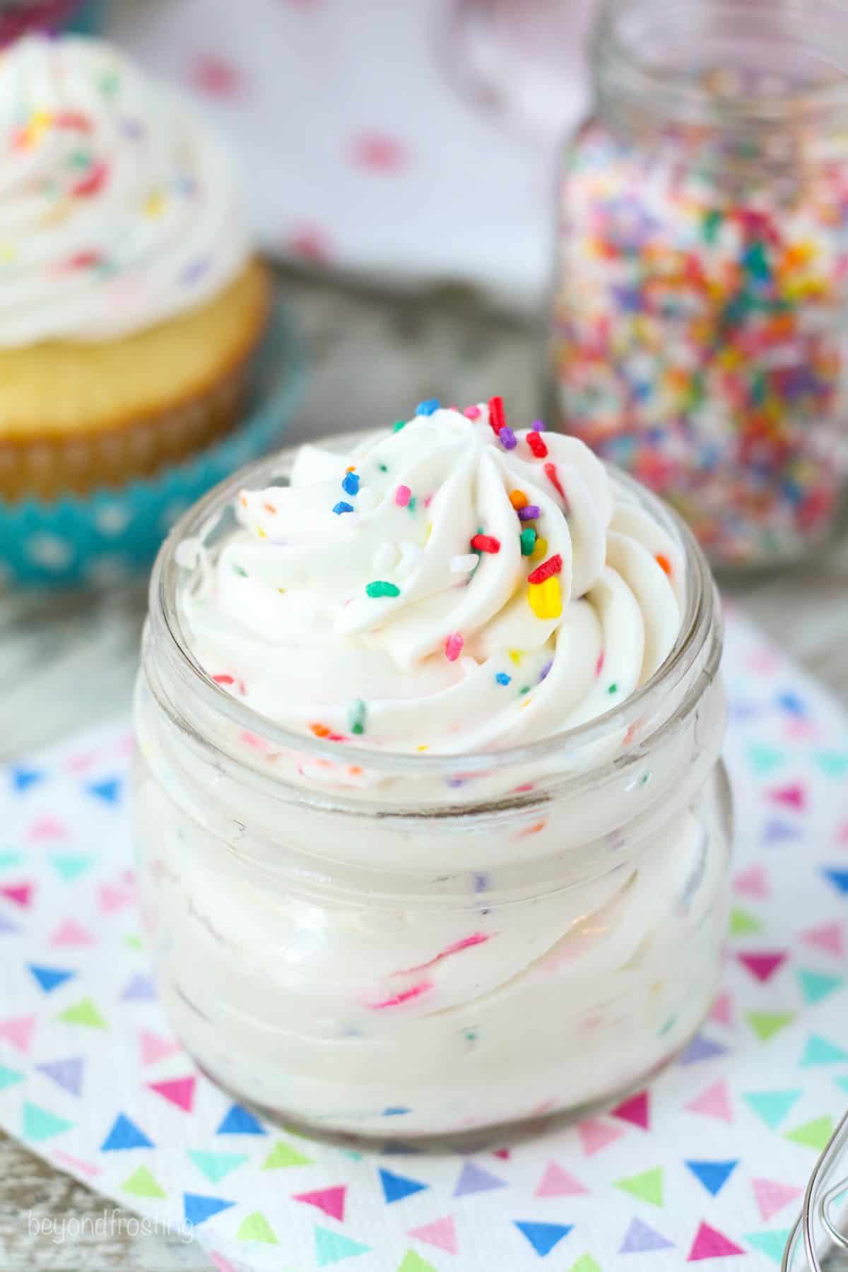 A glass jar of cake batter whipped cream in a pattern napkin