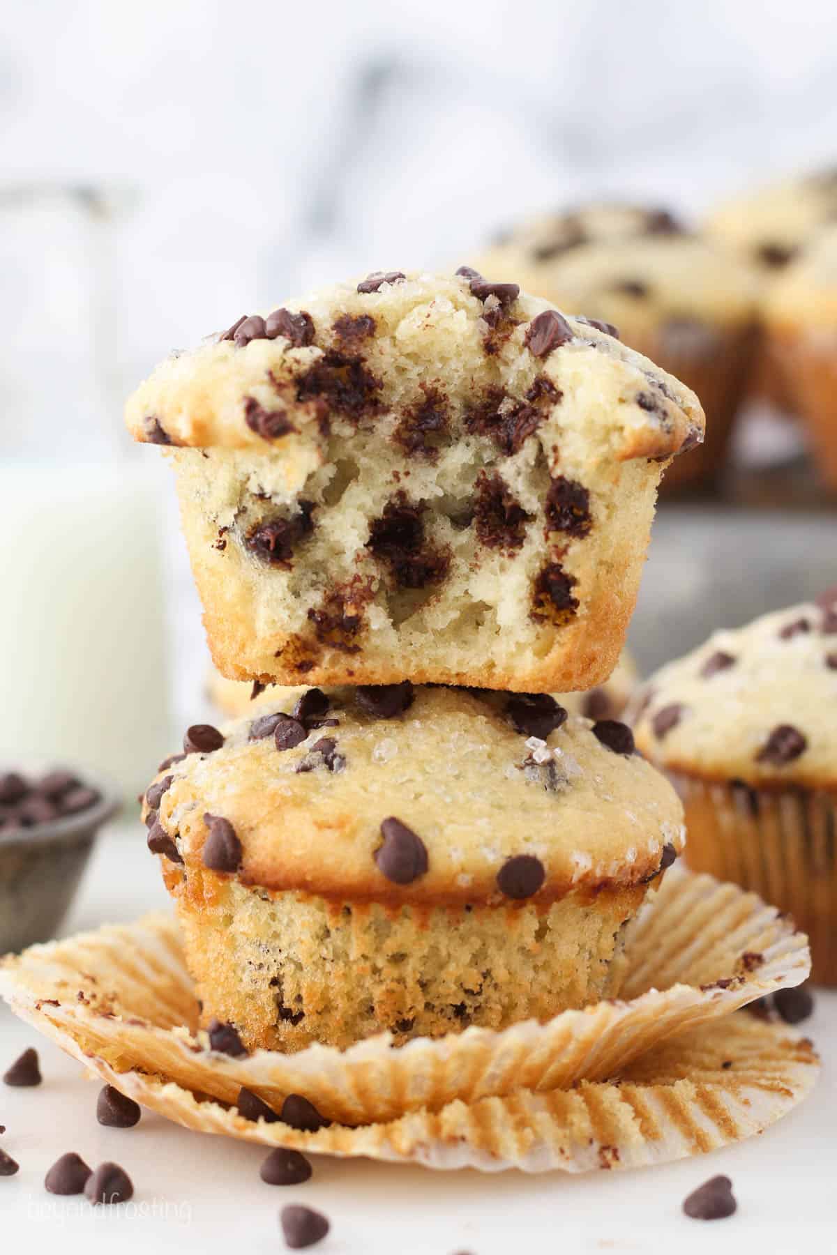 Two chocolate chip muffins stacked on top of each other, one with a bite missing