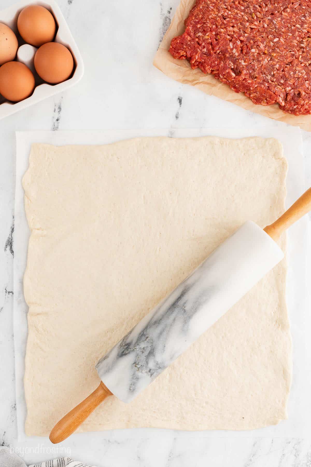 a square of pizza dough rolled out on a piece of parchment paper