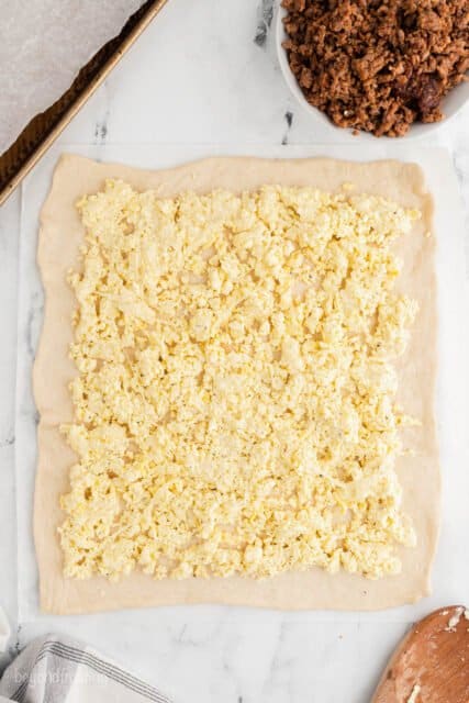 overhead of ricotta and egg filling layered on pizza dough