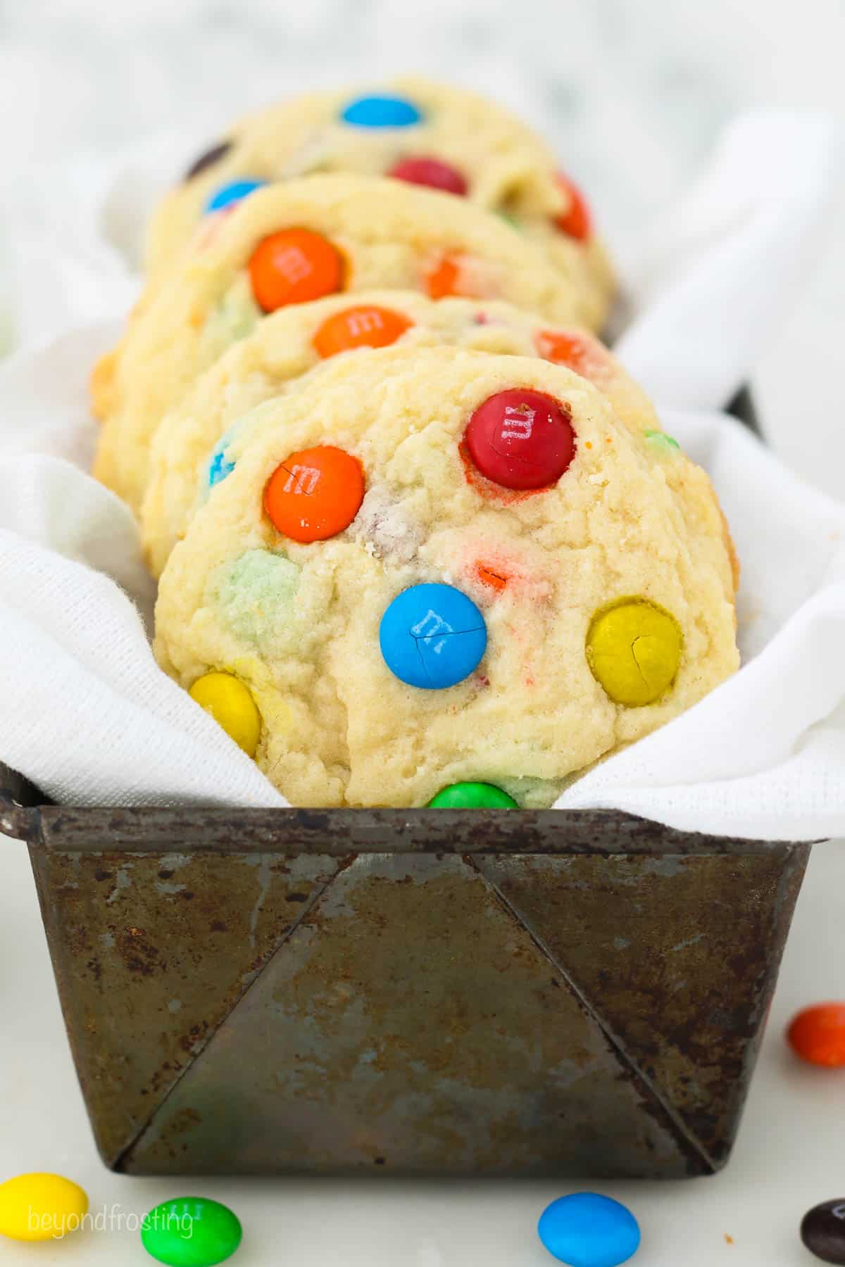 A cloth-lined tin filled with M&M cookies.