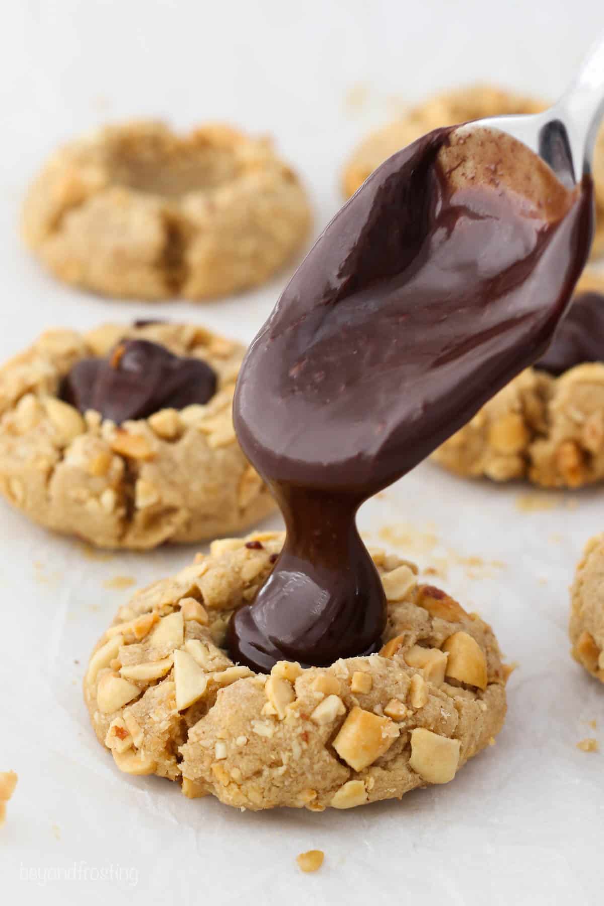 Chocolate dripping off a spoon into a peanut butter cookie