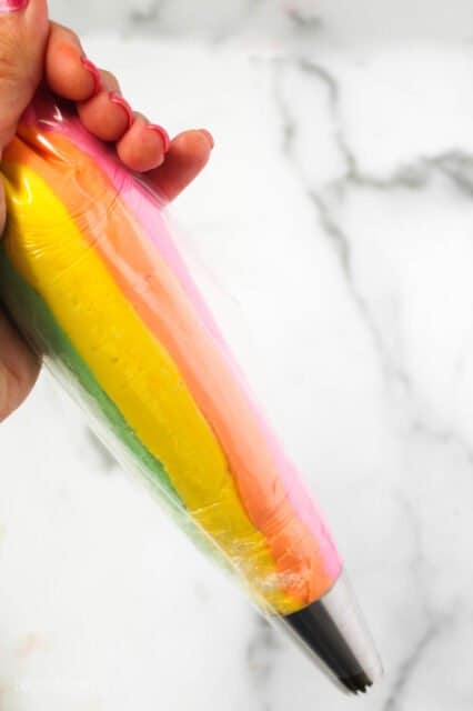 A piping bag of rainbow colored frosting