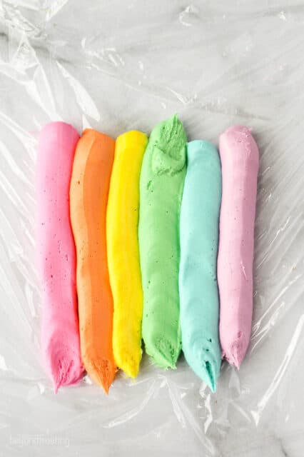 6 rows of different colored frosting on a piece of plastic wrap