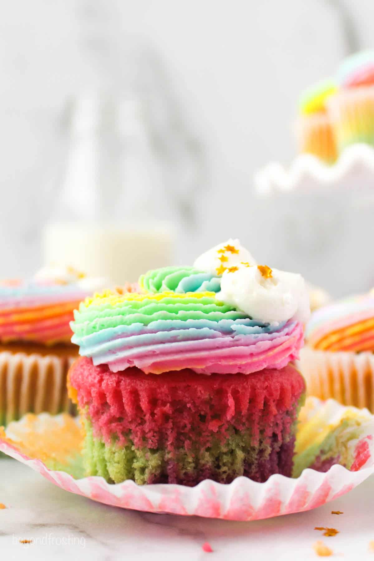 Angled view of a rainbow cupcake with rainbow frosting
