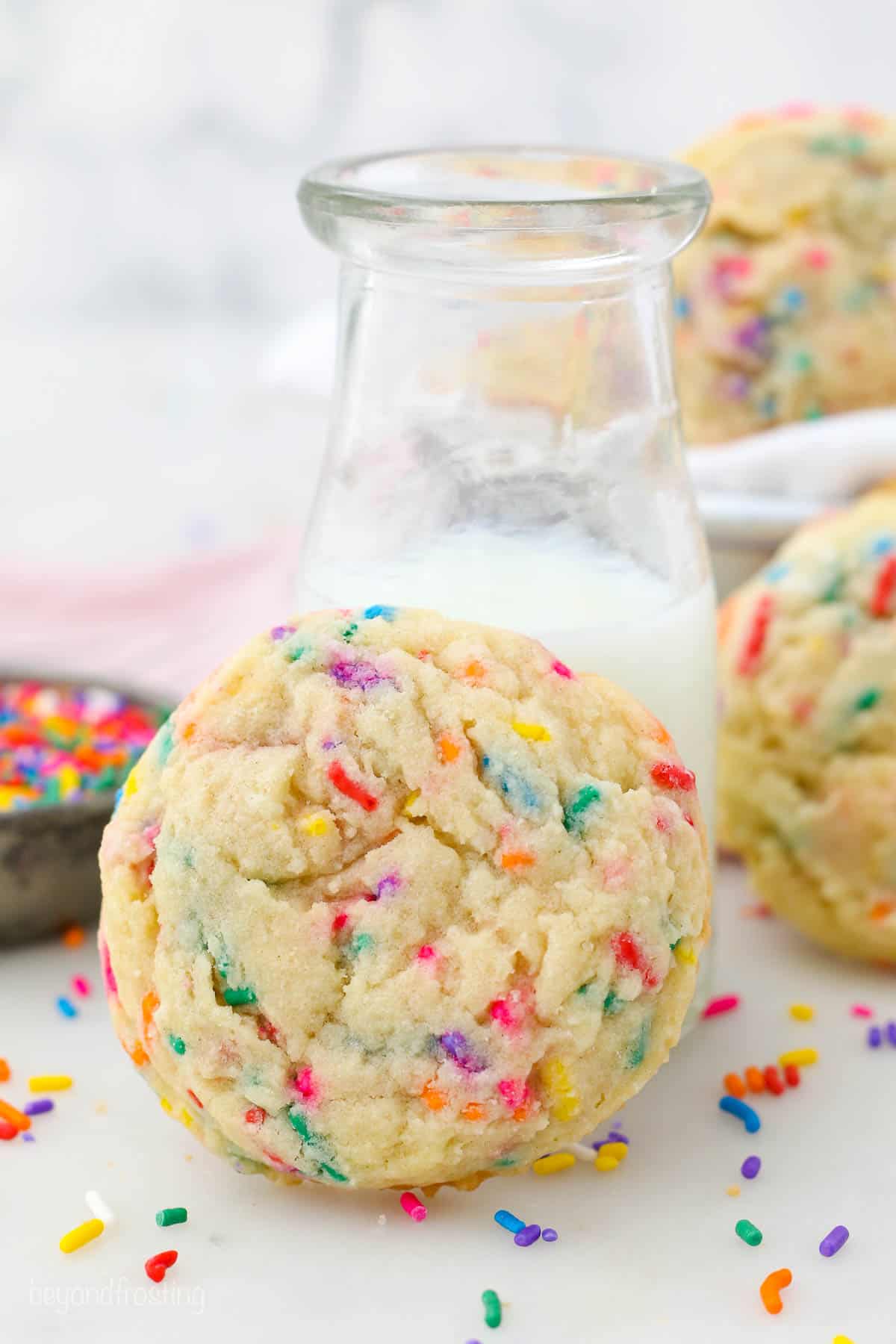 one sprinkle cookie leaning on a jar of milk