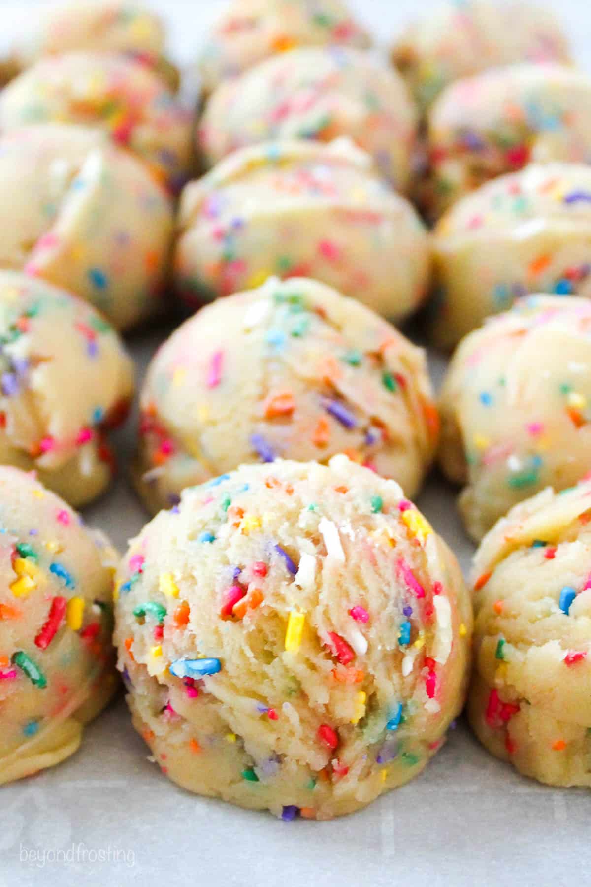 sprinkle cookie dough balls lined on a piece of parchment paper