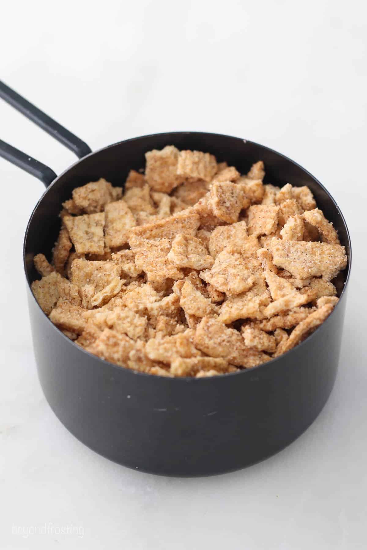 measuring cup filled with Cinnamon Toast Crunch cereal