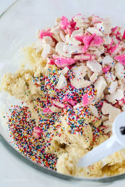 A mixing bowl with cookie dough, sprinkles and broken circus animal cookies