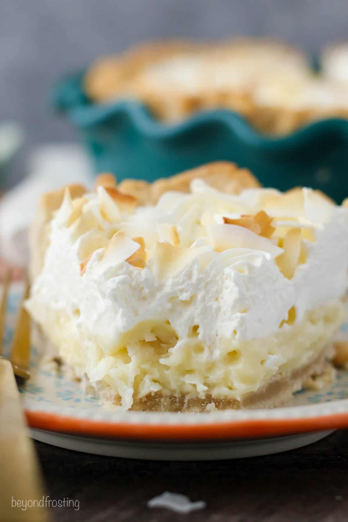 straight on view of a slice of coconut cream pie on a plate with a bite out