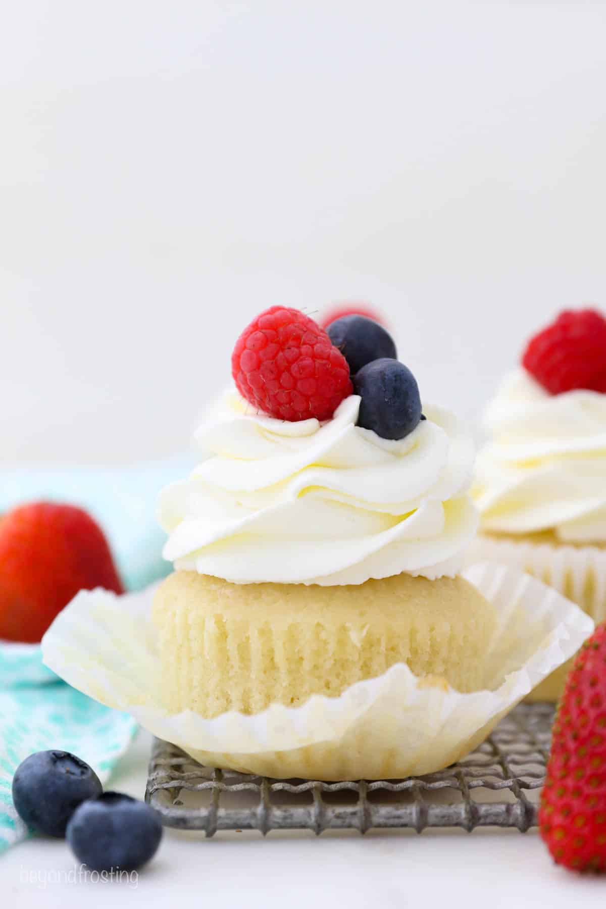 A cupcake with the wrapped pulled down is topped with berries