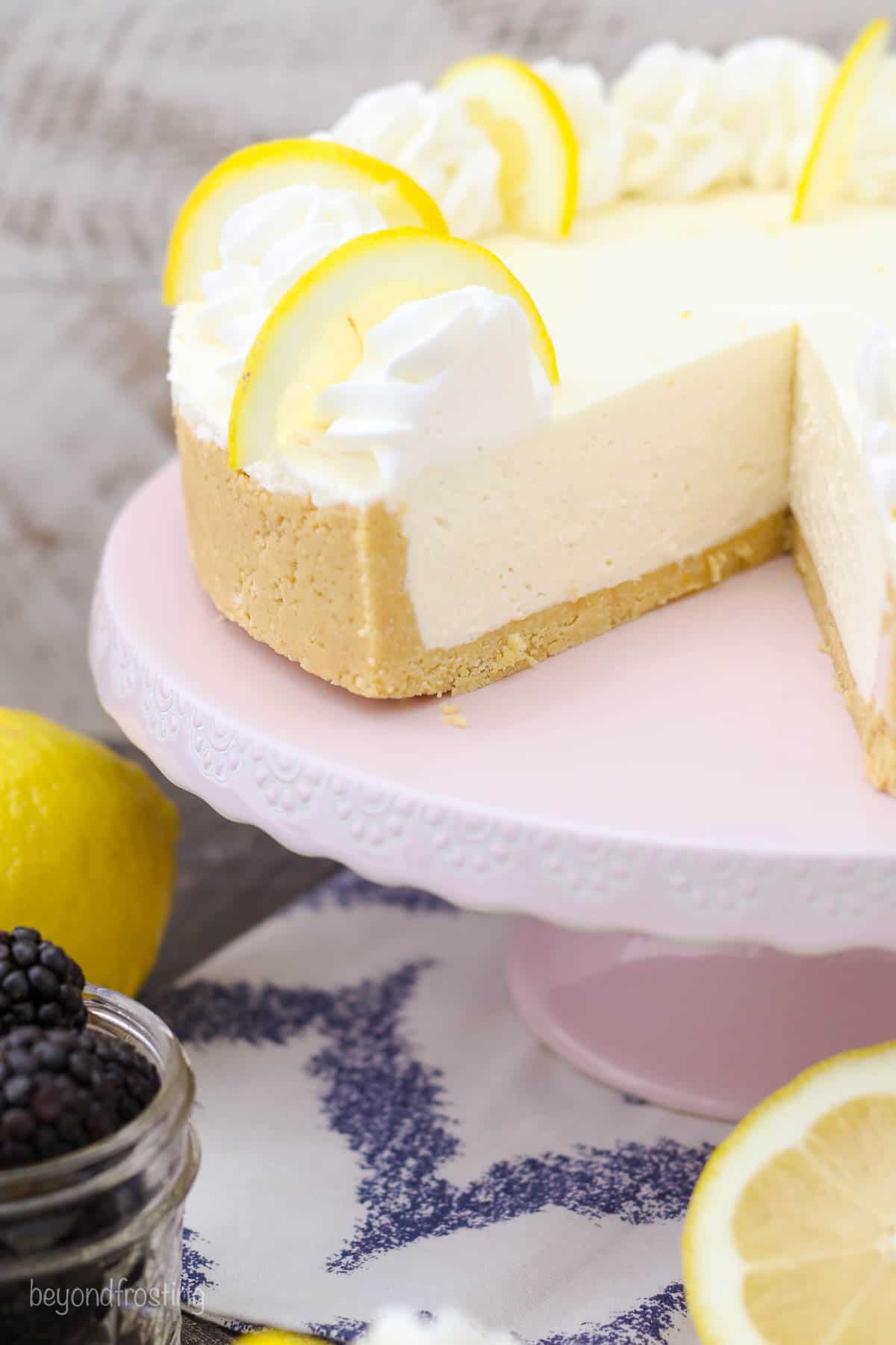 lemon cheesecake on a serving platter with a slice cut out