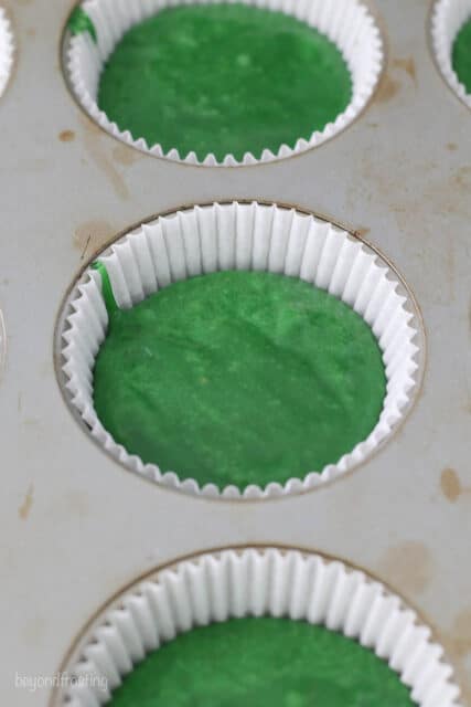 green cupcake batter in a cupcake pan