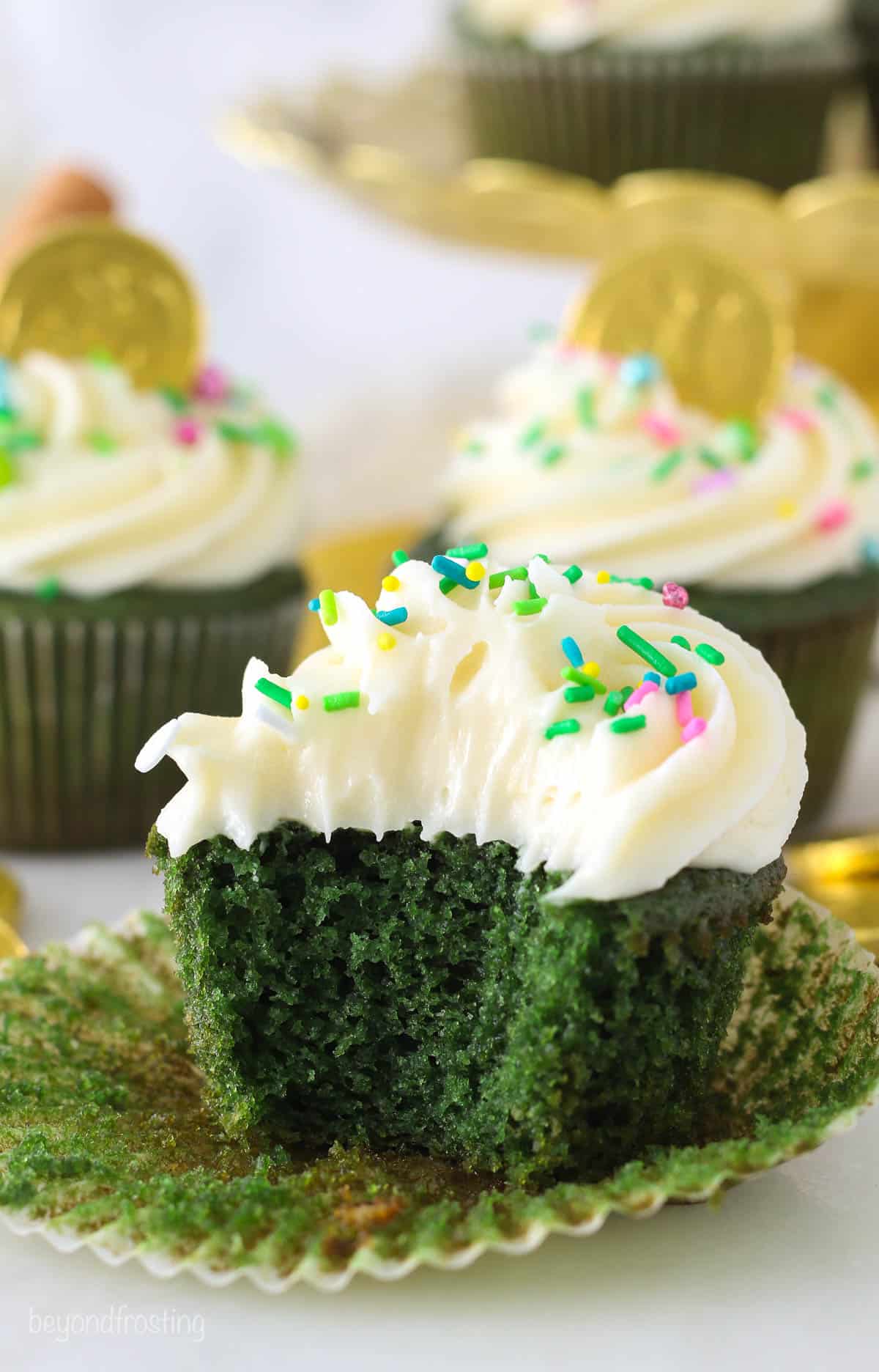 A frosted green velvet cupcake with a bite taken from it