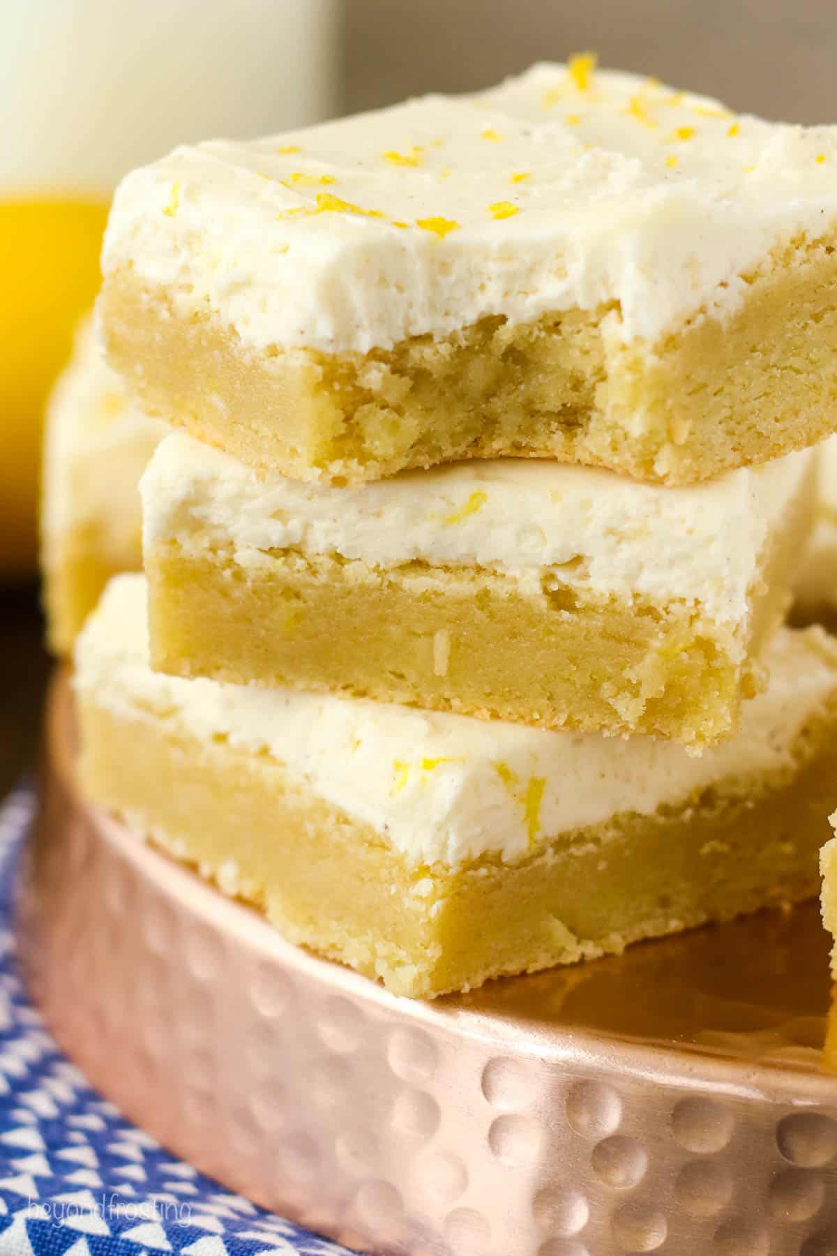 three lemon cookie bars stacked with a bite out of the top cookie bar