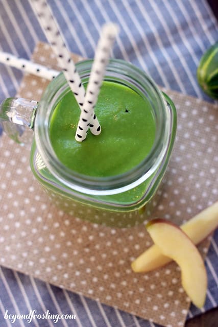 A close-up shot of a green smoothie inside of a glass Mason jar with a handle