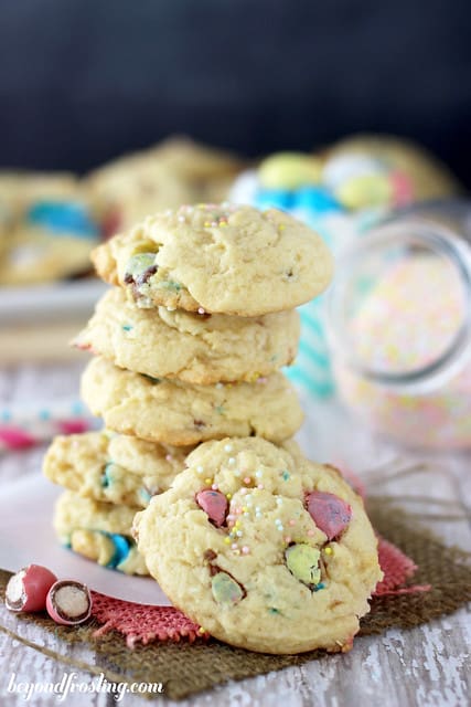 A stack of Easter cookies on top of two wicker coasters with another cookie leaning against the stack
