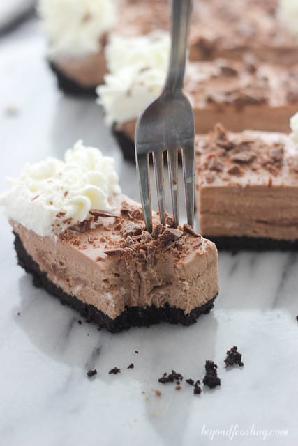 A dessert fork digging into the creamy filling of a chocolate mousse tart