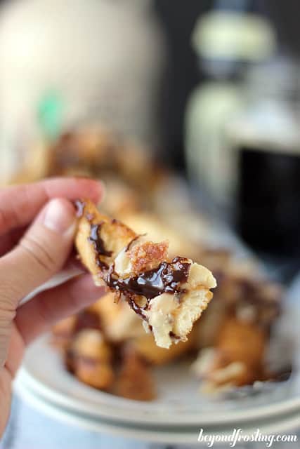 A close-up shot of a donut fry drizzled with hot fudge and maple glaze