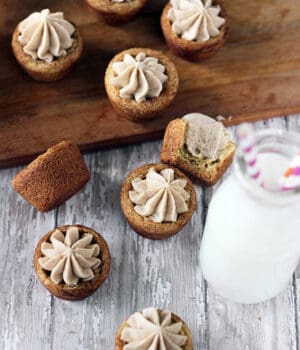 A bunch of snickerdoodle cookie cups scattered on a dining table with a jar of milk beside them