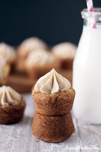 A maple cinnamon cookie cup with frosting sitting on top of an upside-down cookie cup with no frosting