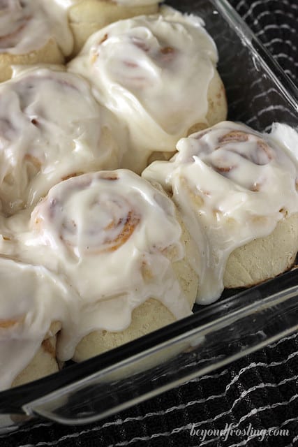 A close-up shot of a pan full of homemade cinnamon rolls covered in icing