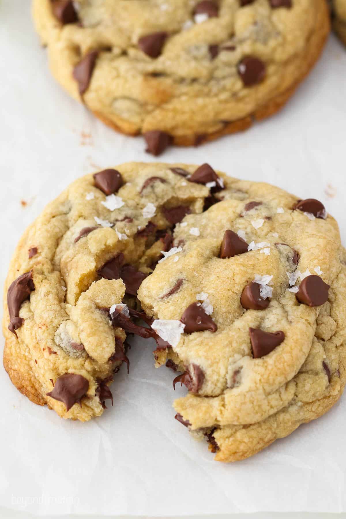 Angled view of a thick giant chocolate chip cookie split in half with a gooey center