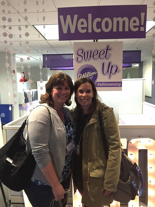 Author posing with another woman in front of a Wilton sign