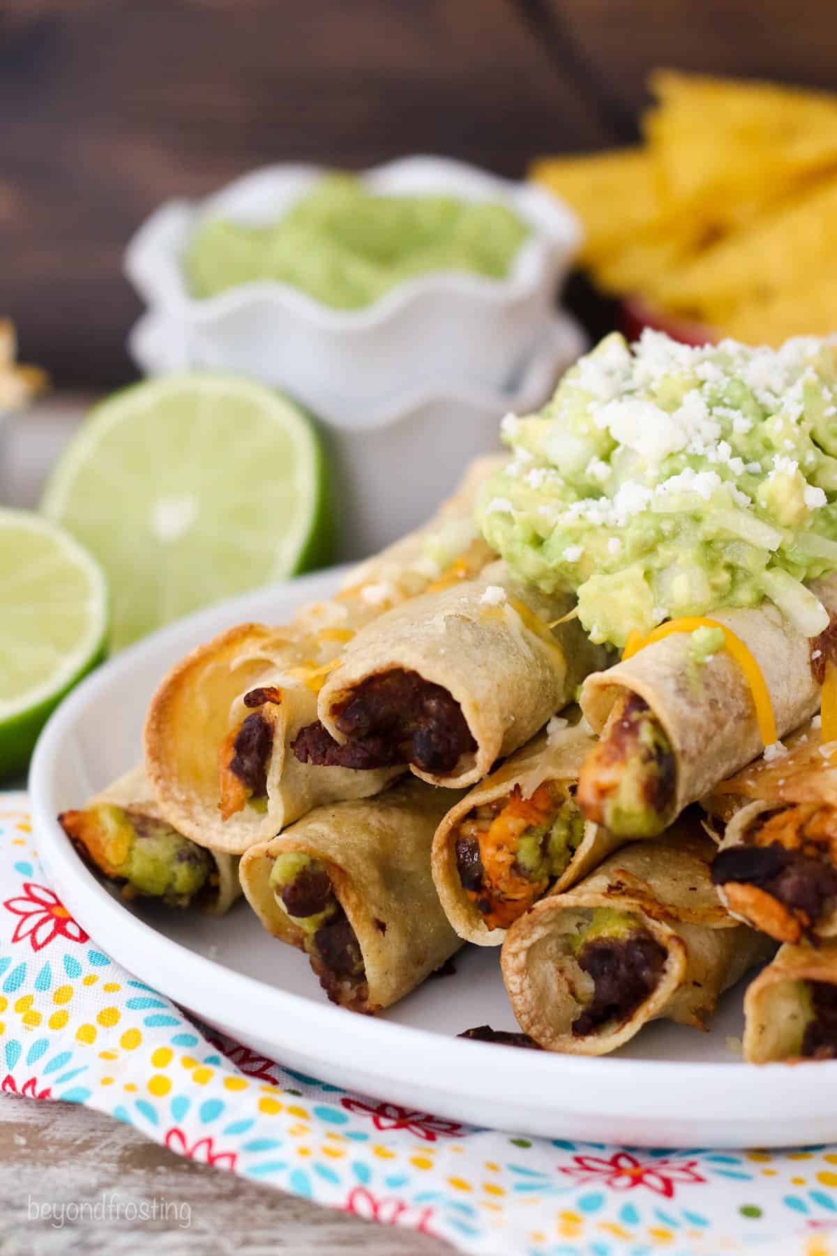 side view of a chicken taquitos piled on a white plate topped with salsa