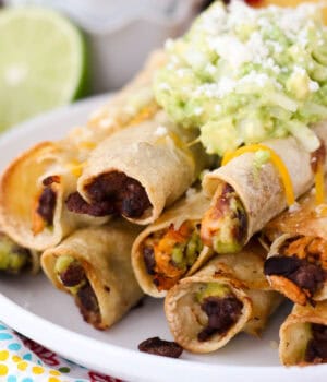 closeup of a pile of chicken taquitos topped with salsa