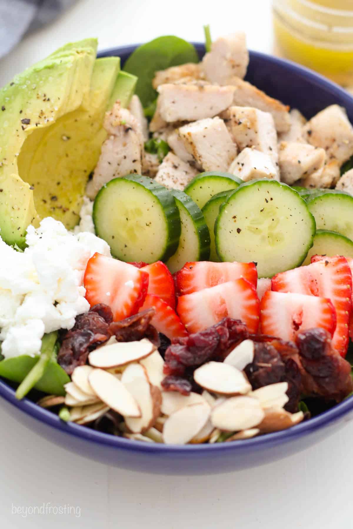 overhead and closeup of a bowl of salad topped with fruits, veggies, and nuts