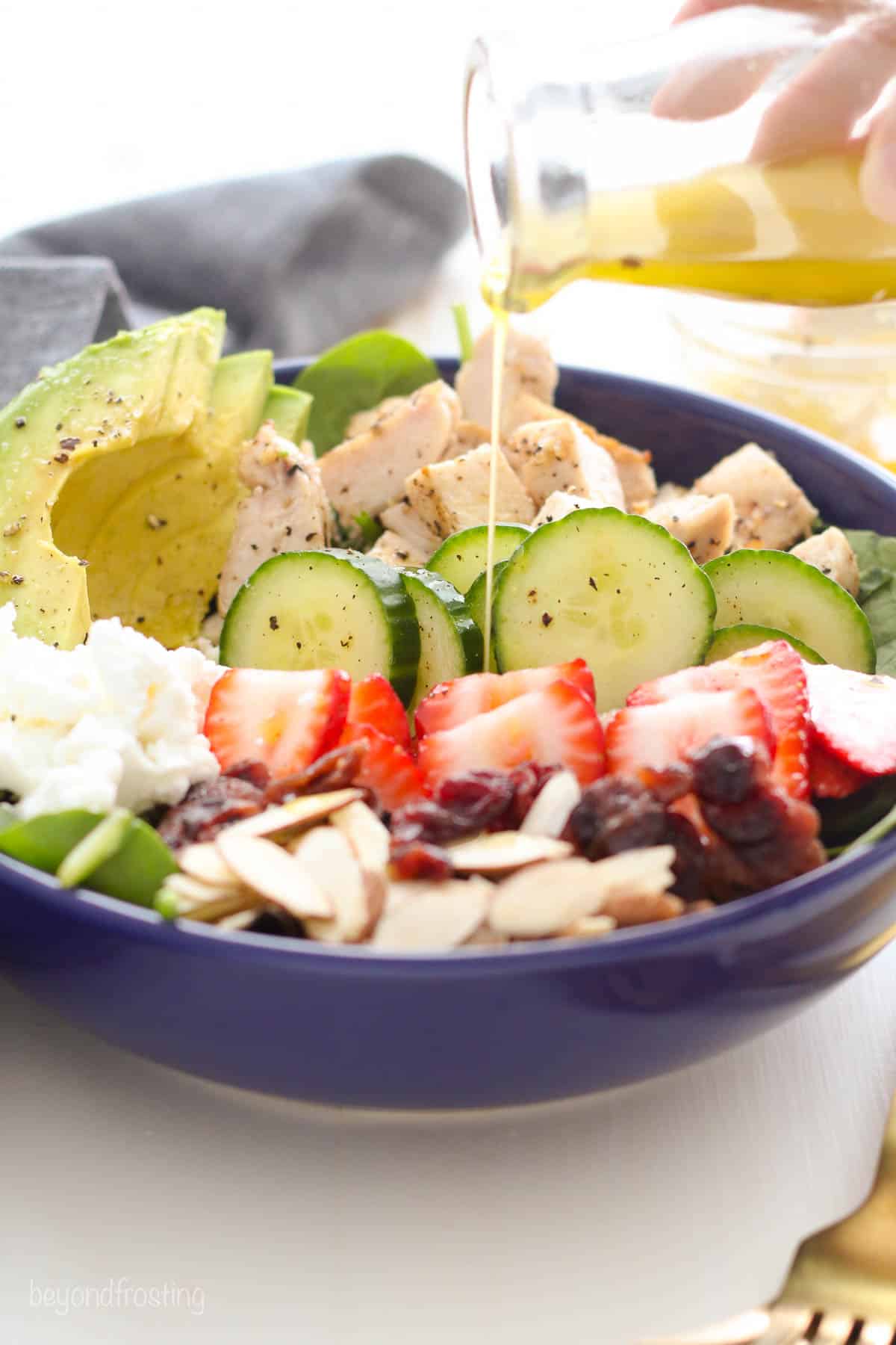 bowl of salad being drizzled with lemon vinaigrette