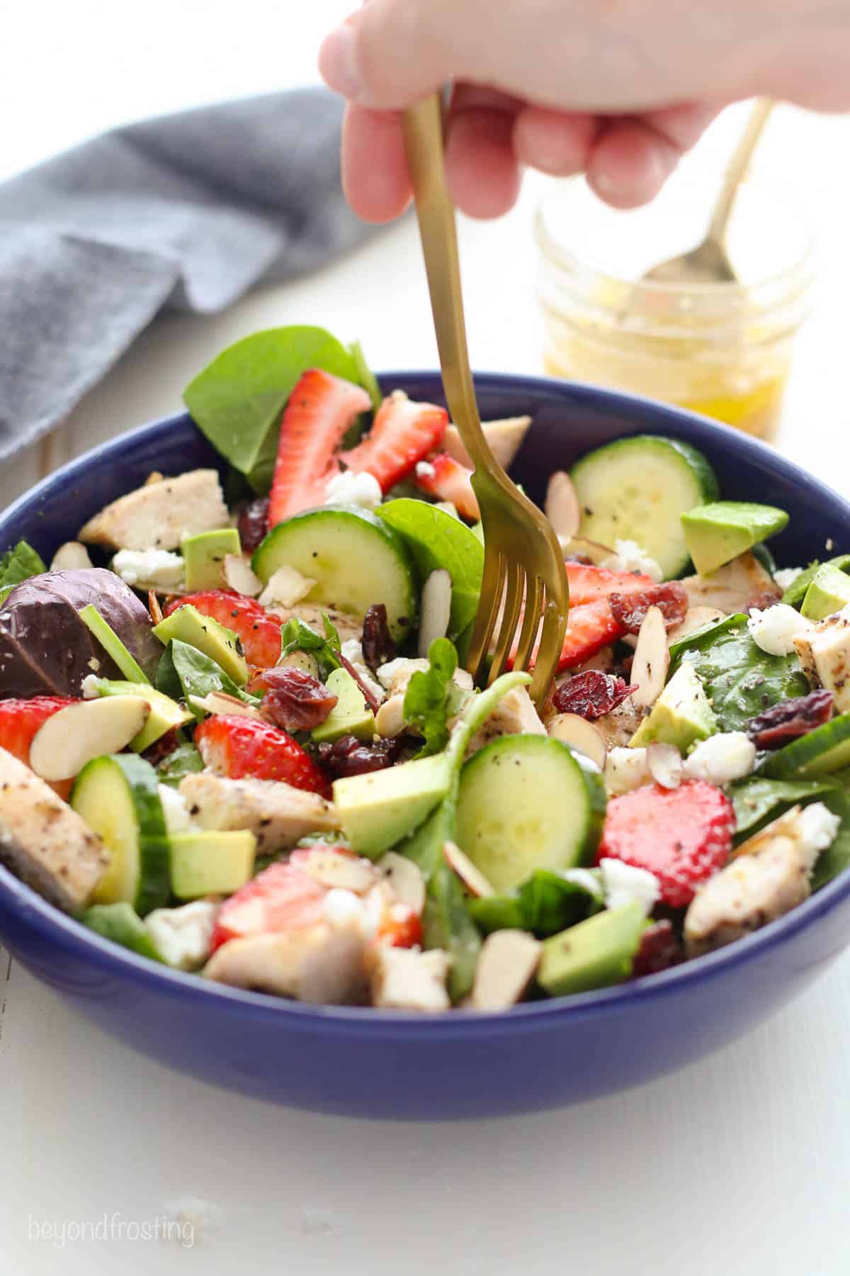 blue bowl filled with salad with a gold fork held