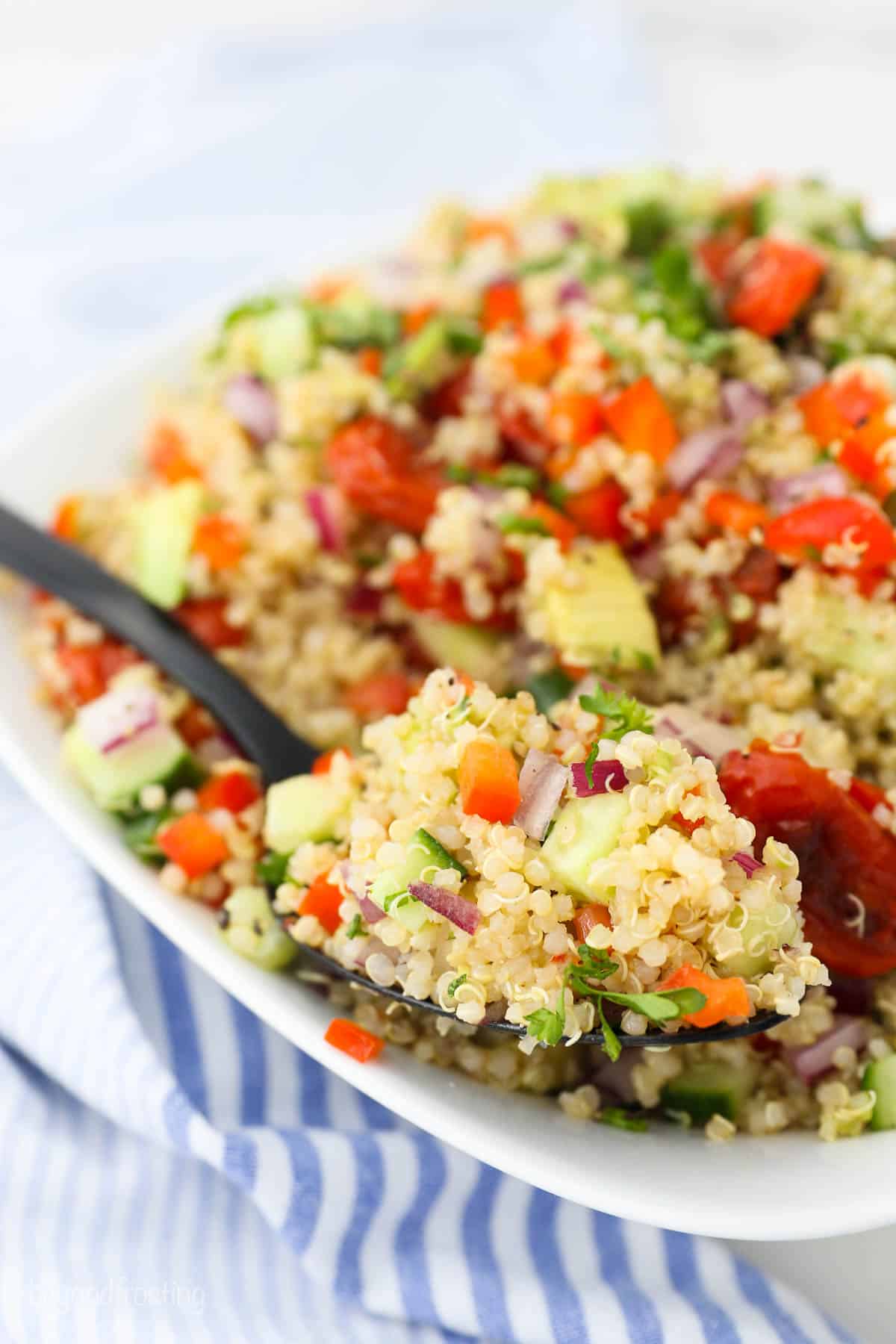 A bowl of vegetable Quinoa salad on a black spoon