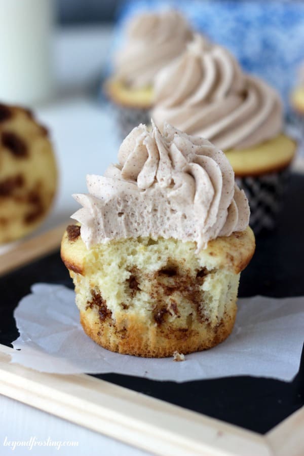 cinnamon roll cupcake with a bite taken out with other cupcakes in the background