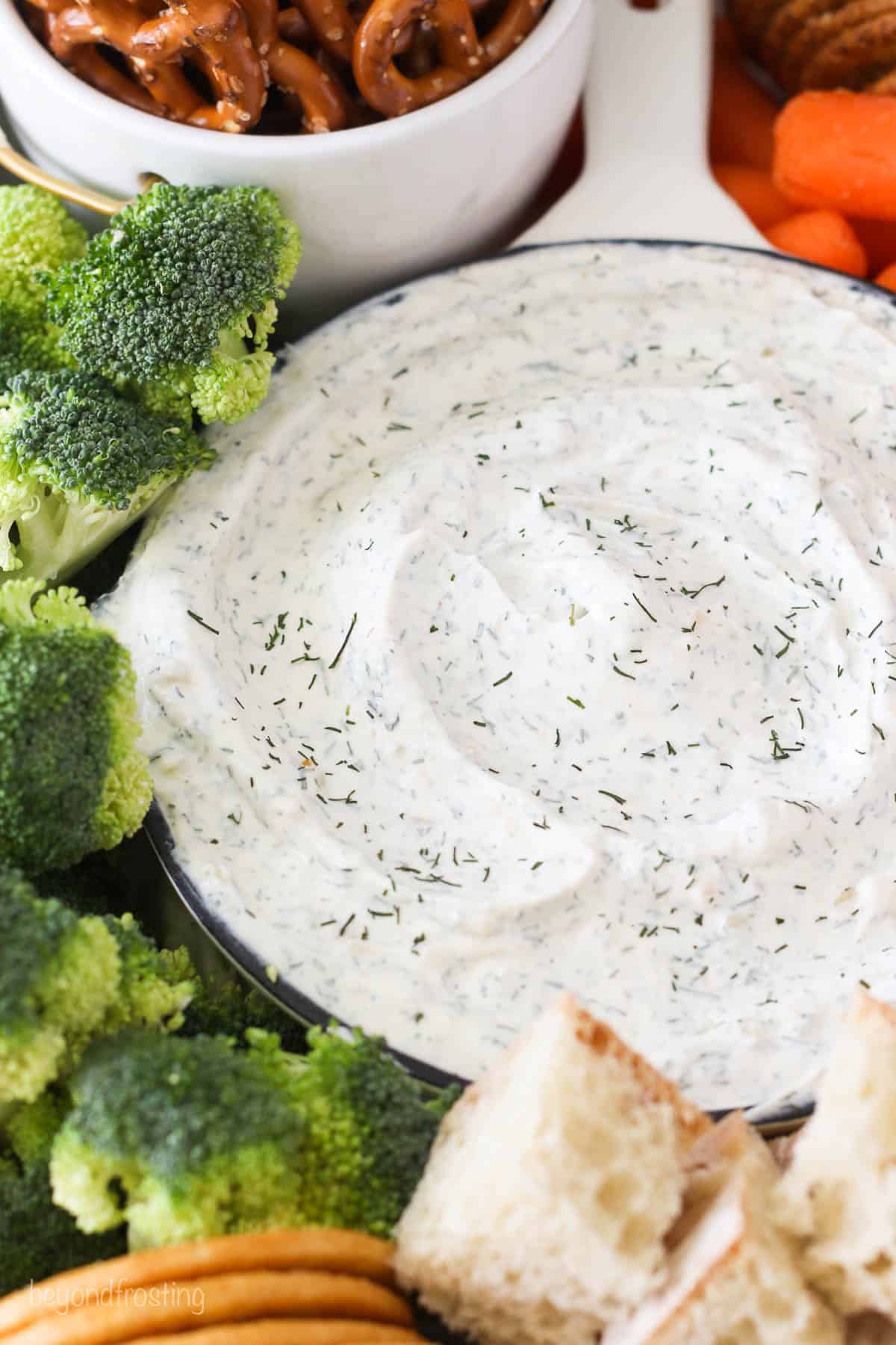 A bowl of dill dip next to broccoli