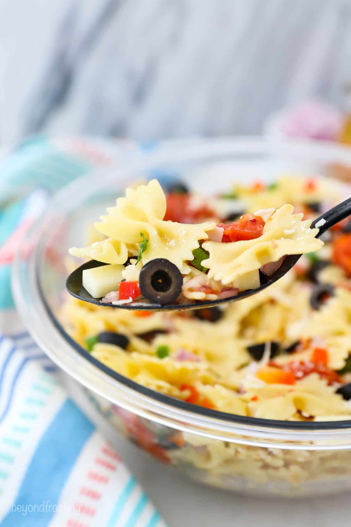 a spoonful of pasta salad held over a bowl